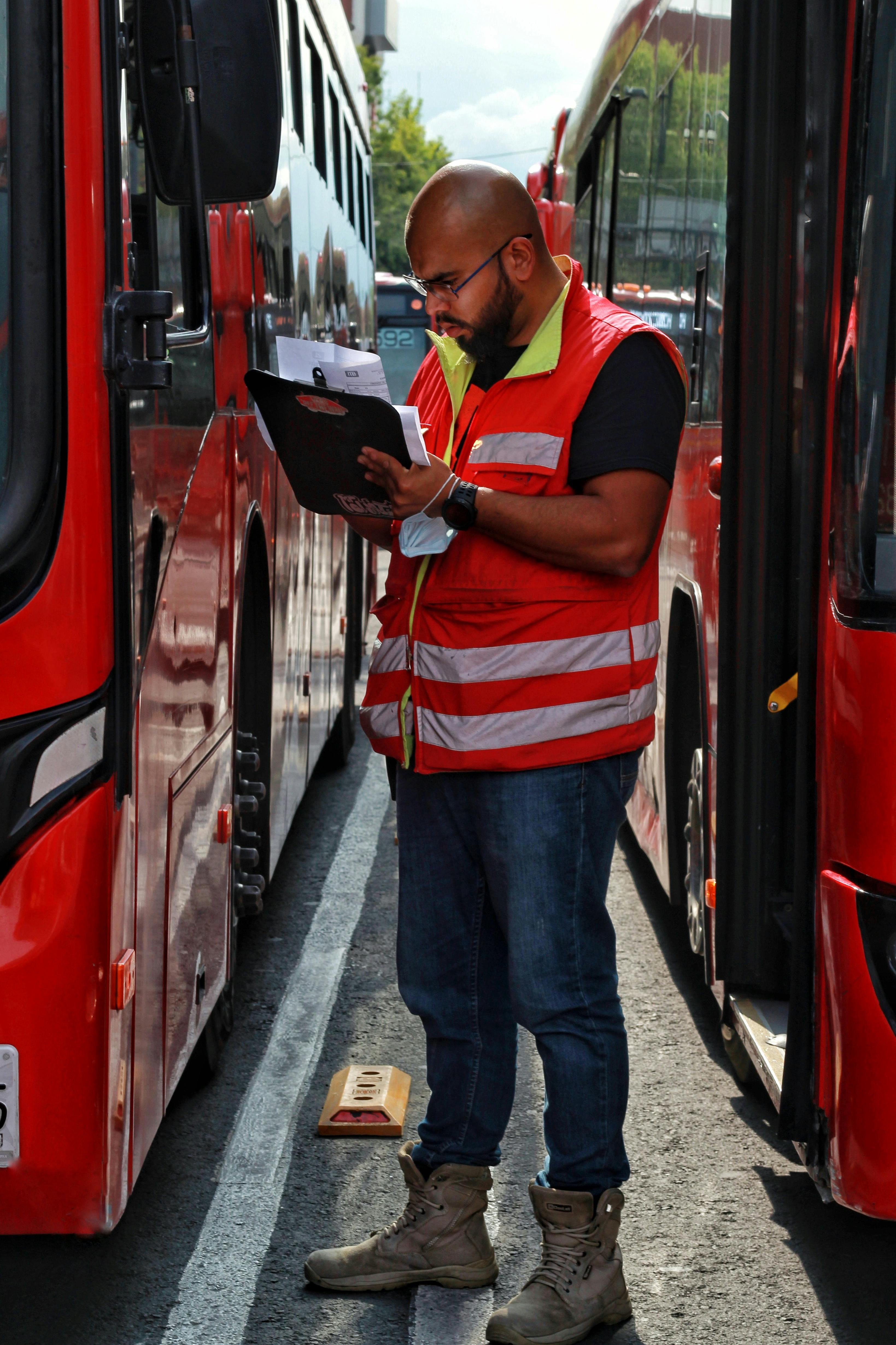 Fleet director reviewing documents while inspecting buses in a transit yard