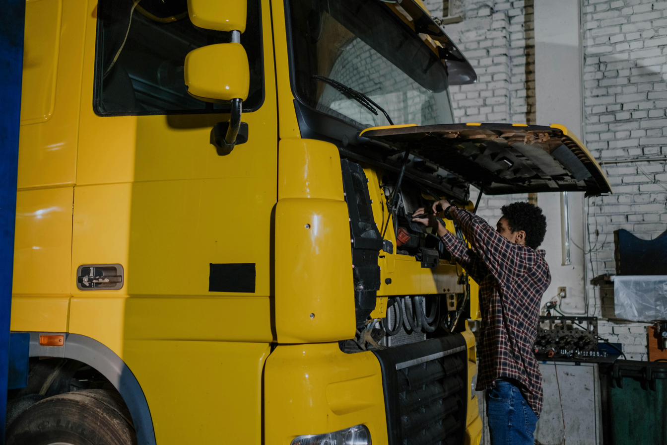 Junior fleet technician reaching into a truck cab during maintenance