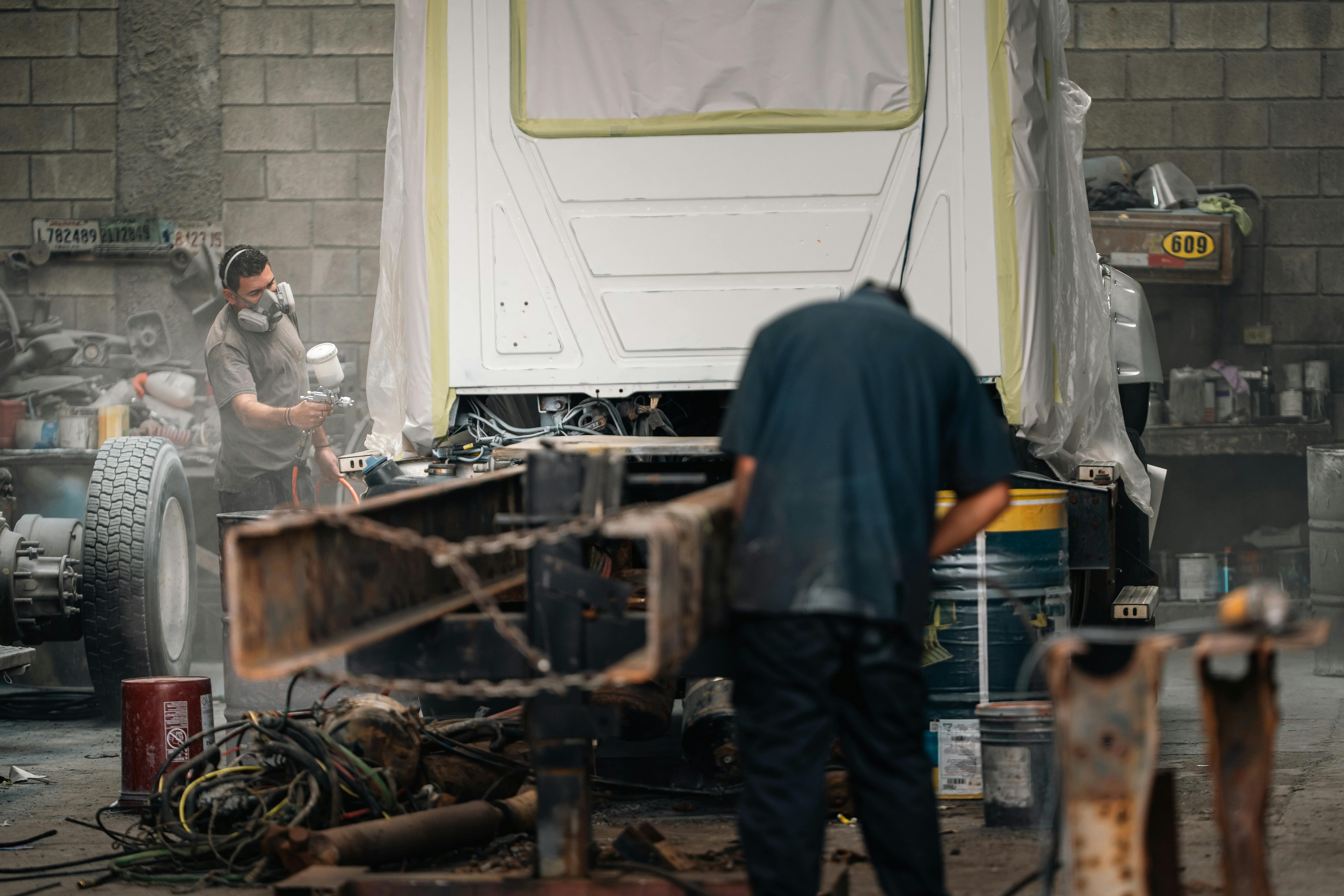 Two transit maintenance technicians working on a bus in the yard